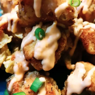 Crispy air-fried Bang Bang Chicken pieces drizzled with creamy chili sauce and topped with chopped green onions