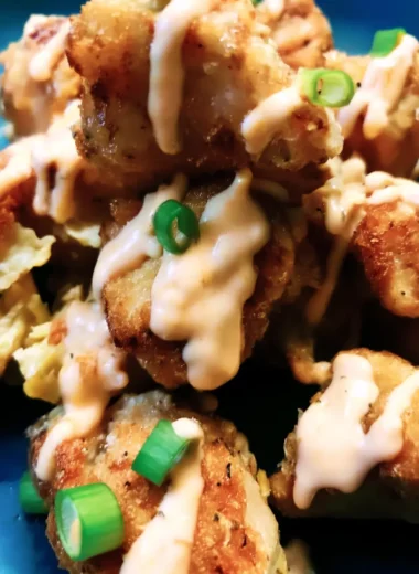 Crispy air-fried Bang Bang Chicken pieces drizzled with creamy chili sauce and topped with chopped green onions