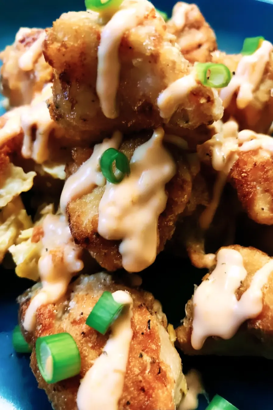 Crispy air-fried Bang Bang Chicken pieces drizzled with creamy chili sauce and topped with chopped green onions