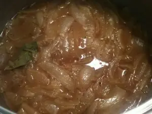 	Pot of caramelized onions and bay leaf simmering in beef broth for a classic french onion soup recipe