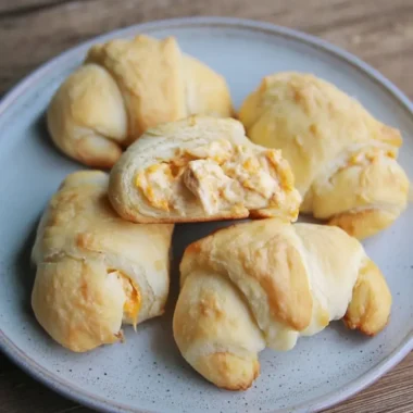 Flaky crescent-roll cheesy garlic chicken wraps arranged on a stoneware plate.