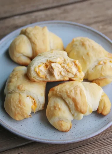 Flaky crescent-roll cheesy garlic chicken wraps arranged on a stoneware plate.