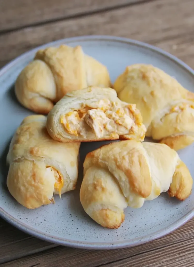 Flaky crescent-roll cheesy garlic chicken wraps arranged on a stoneware plate.