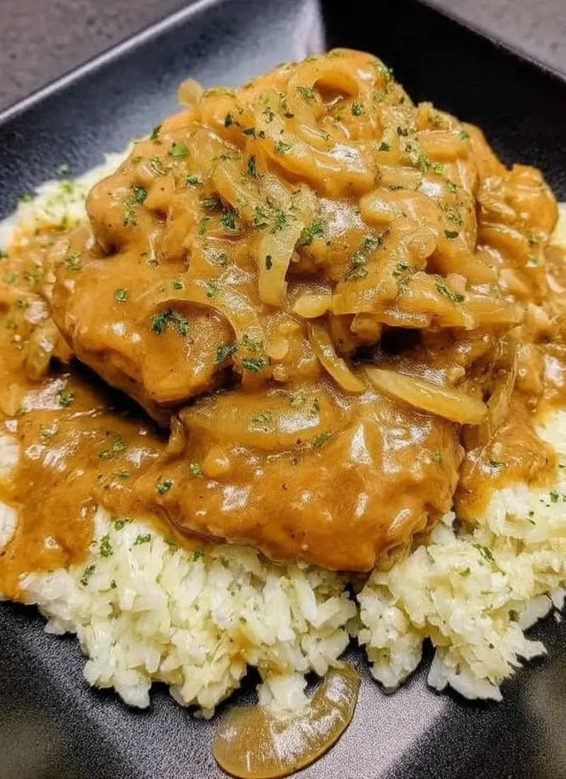 Creamy smothered chicken and rice—pan-seared chicken cutlets blanketed in rich onion gravy, piled high on fluffy white rice.