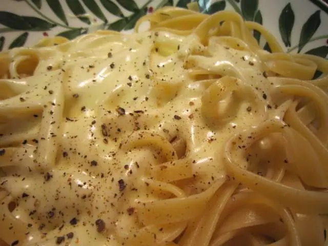 Close-up of cooked Fettuccine Alfredo topped with creamy sauce and cracked black pepper