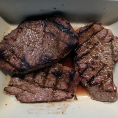 Grilled beef sirloin steak bites with dark char marks resting in their savory juices.