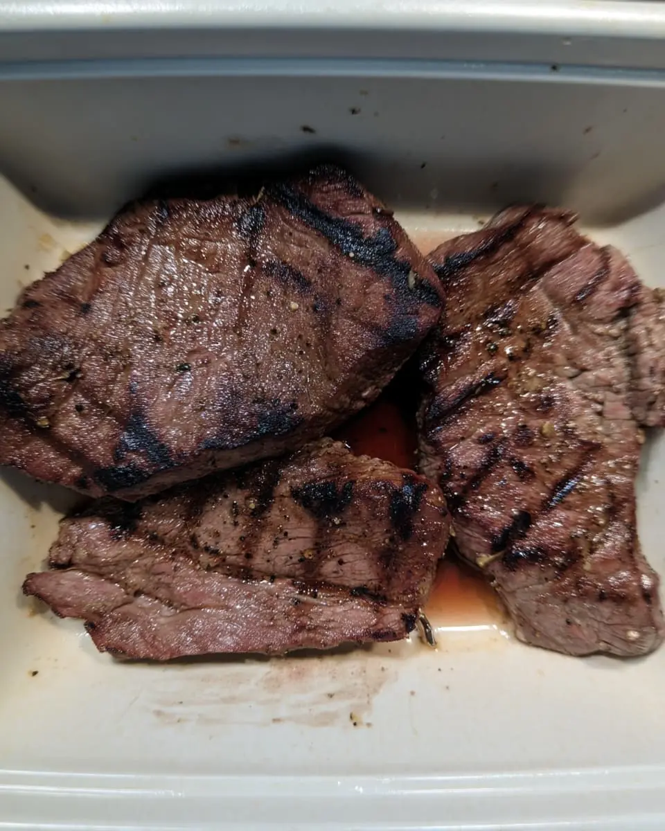 Grilled beef sirloin steak bites with dark char marks resting in their savory juices.