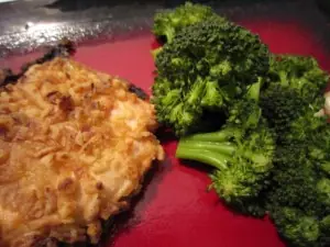 Crispy onion crusted chicken breast served alongside steamed broccoli on a red plate