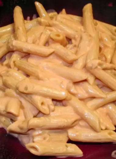 Perfectly coated penne alla vodka pasta in a dark bowl showing creamy pink sauce clinging to every ridged noodle