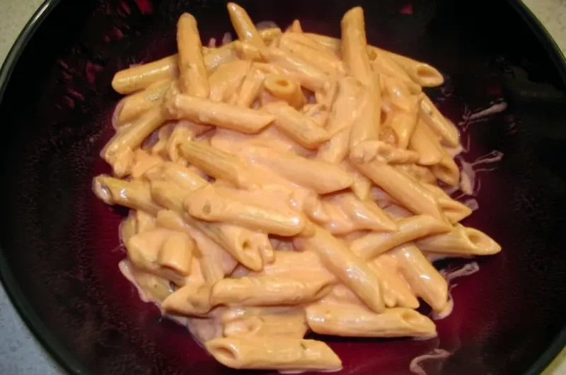 Perfectly coated penne alla vodka pasta in a dark bowl showing creamy pink sauce clinging to every ridged noodle