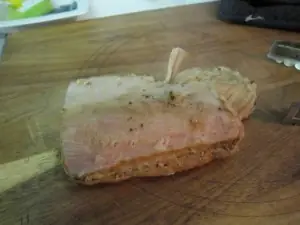 Cooked pork roast on a wooden cutting board before shredding.