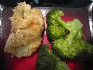 Stuffed chicken breast rolled with mozzarella cheese and topped with shrimp, served with steamed broccoli on a red plate